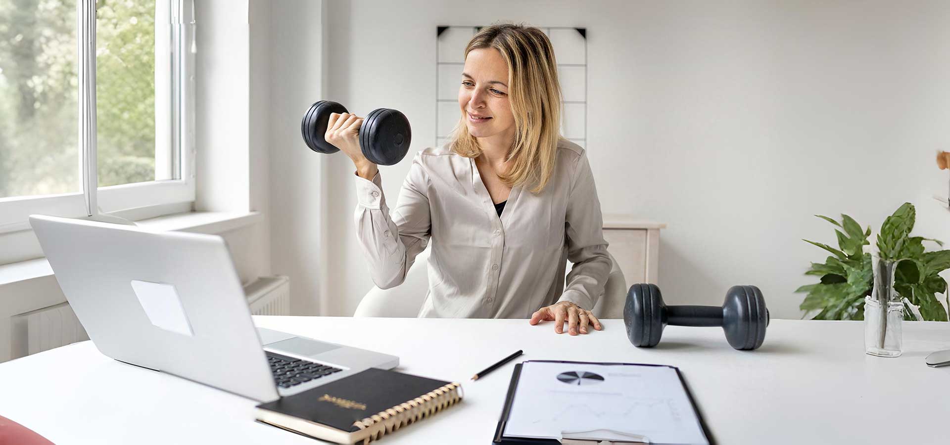 Junge Frau in Büro stemmt Hantel