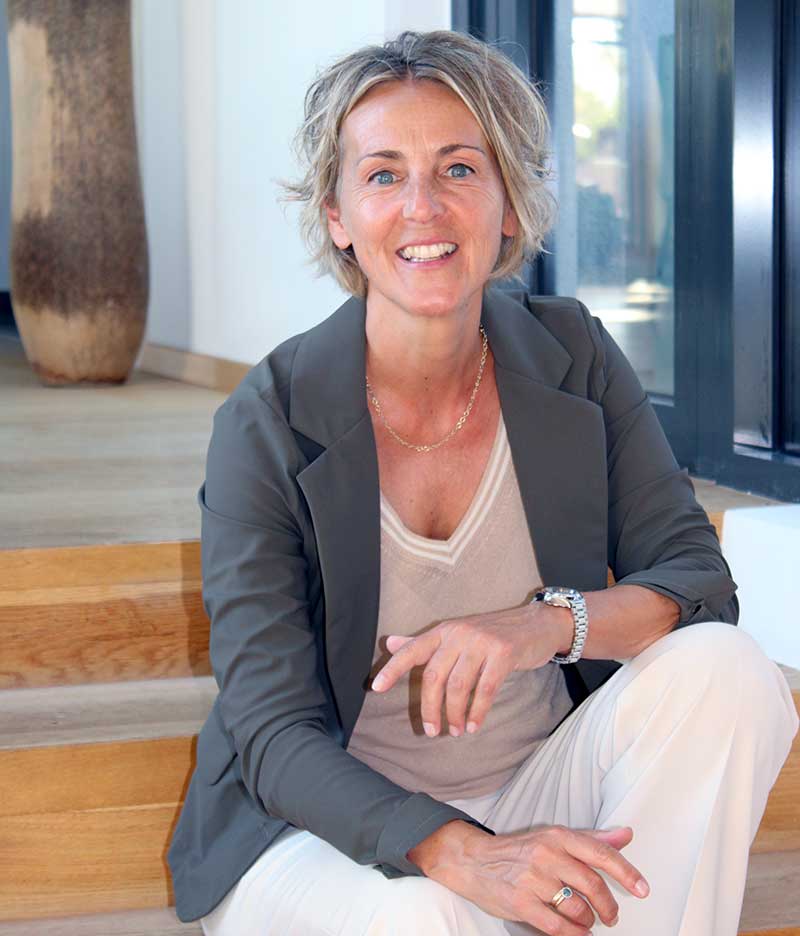 Lächelnde Sabine Wolfsgruber sitzt in sportlicher Kleidung auf einer Treppe